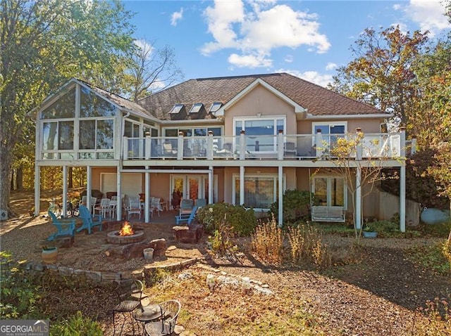 rear view of property with a fire pit, stucco siding, a deck, a sunroom, and a patio