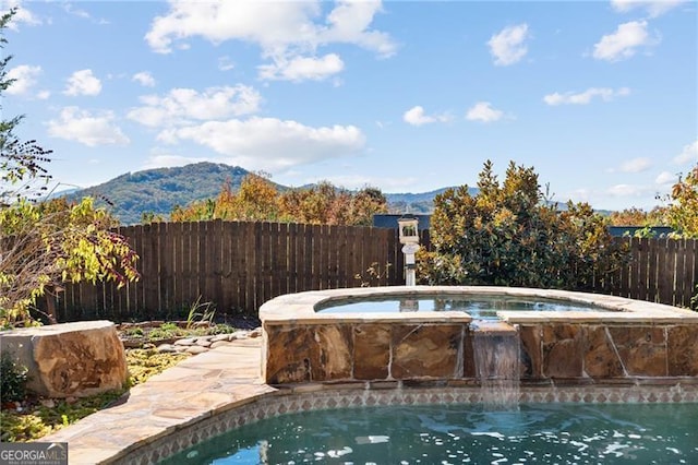 view of swimming pool with an in ground hot tub, a mountain view, and pool water feature