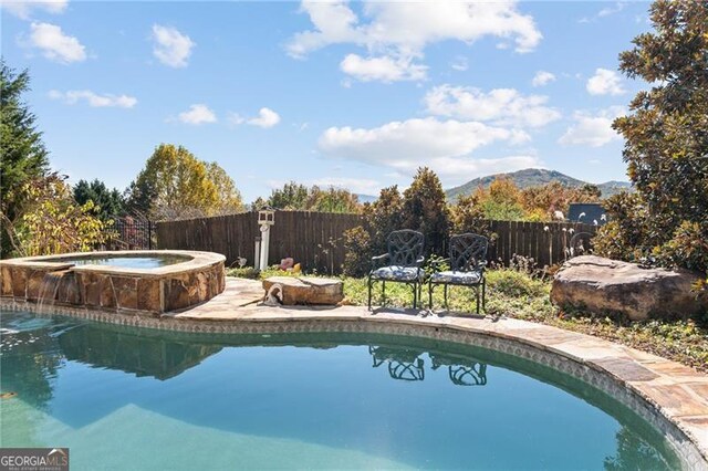 view of pool featuring a mountain view and an in ground hot tub