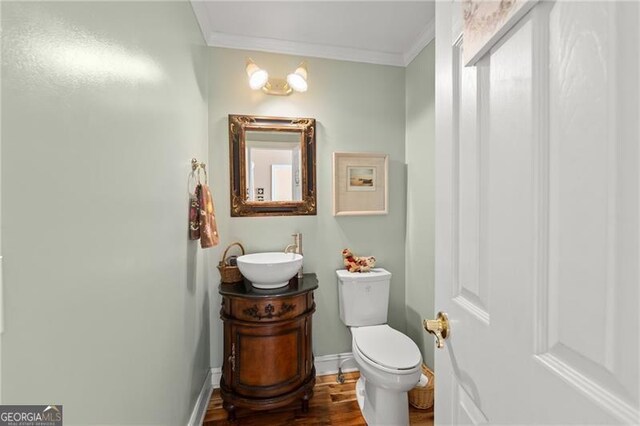 bathroom with an inviting chandelier, toilet, wood-type flooring, vanity, and ornamental molding