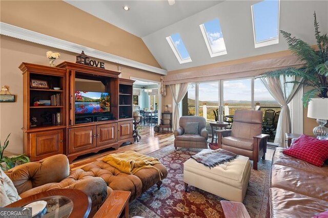 living room featuring hardwood / wood-style flooring, high vaulted ceiling, and a skylight