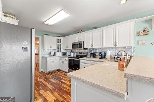 kitchen with backsplash, light countertops, appliances with stainless steel finishes, white cabinets, and a sink