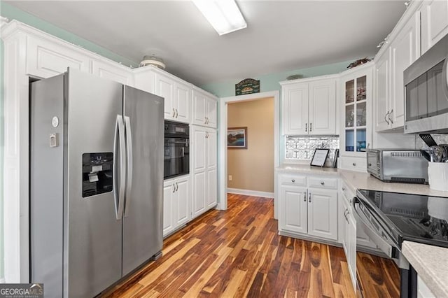 kitchen featuring appliances with stainless steel finishes, white cabinetry, decorative backsplash, and dark hardwood / wood-style floors