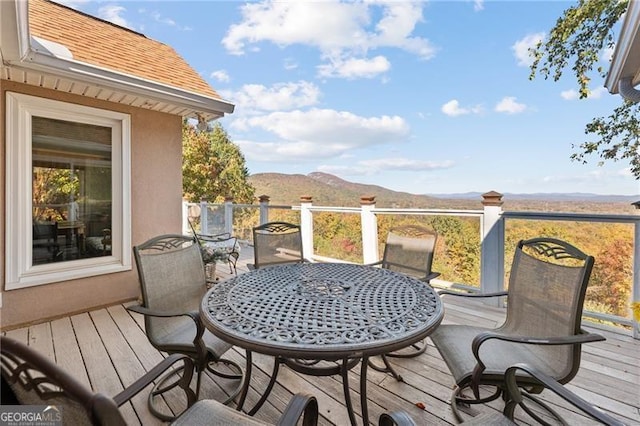 deck with outdoor dining space and a mountain view