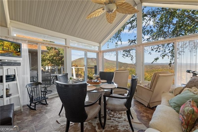 sunroom / solarium with ceiling fan, a mountain view, and vaulted ceiling