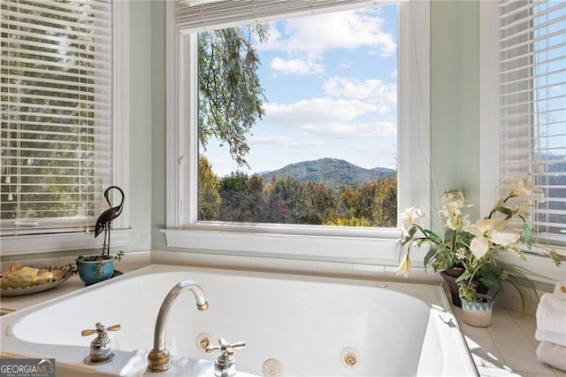 bathroom featuring a tub with jets and a mountain view