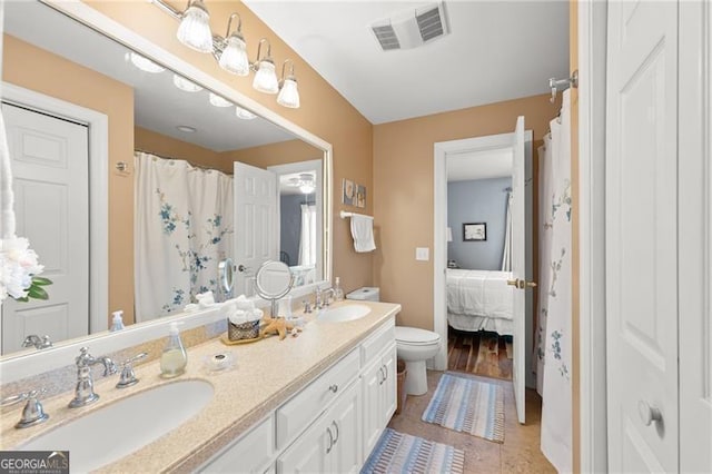 bathroom with double vanity, toilet, visible vents, and a sink