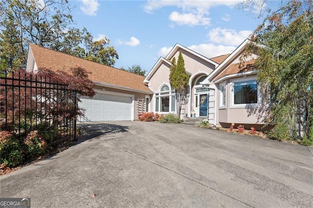 view of front facade with stucco siding, a garage, and driveway