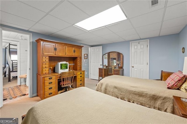 bedroom featuring light carpet and a drop ceiling