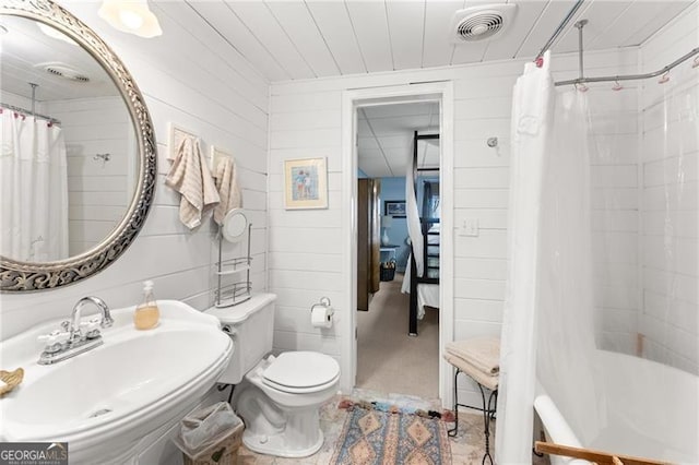 full bathroom with toilet, sink, shower / tub combo, and wooden walls