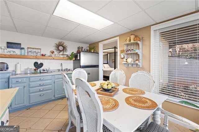 tiled dining space featuring a drop ceiling and sink