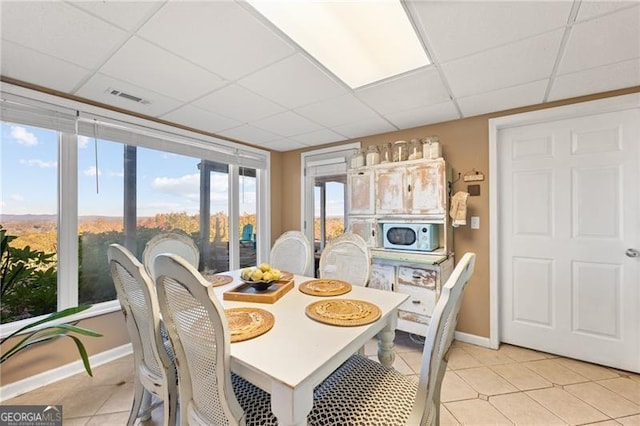 tiled dining room with a drop ceiling