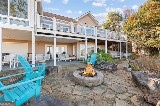 back of property featuring a patio, a balcony, an outdoor fire pit, and stucco siding