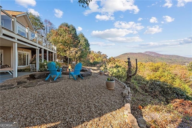 view of yard featuring a mountain view, a patio, a balcony, and an outdoor fire pit