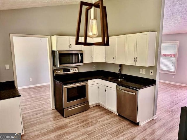 kitchen featuring appliances with stainless steel finishes, light hardwood / wood-style floors, white cabinetry, and a textured ceiling