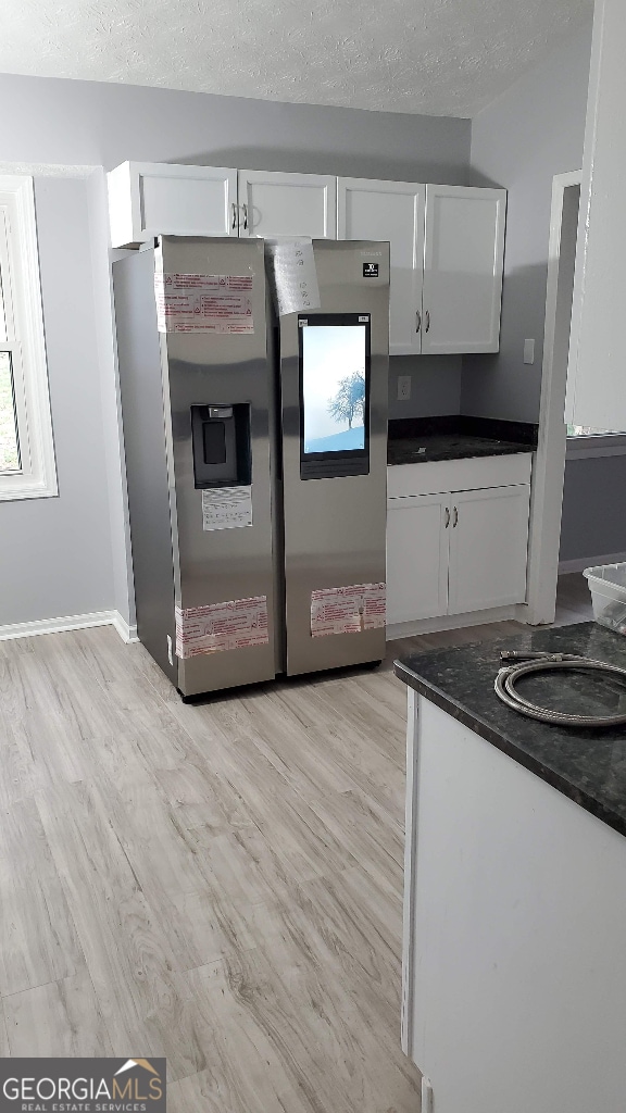 kitchen with light wood-type flooring, white cabinetry, and stainless steel refrigerator with ice dispenser