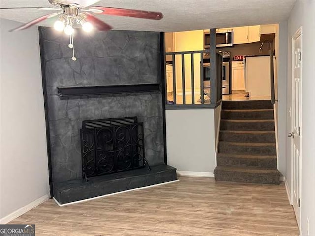 unfurnished living room with a textured ceiling, ceiling fan, and hardwood / wood-style floors