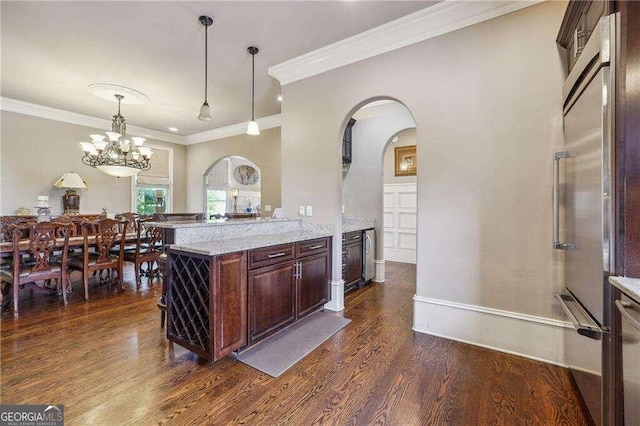 kitchen featuring crown molding, dark wood-type flooring, light stone counters, and hanging light fixtures