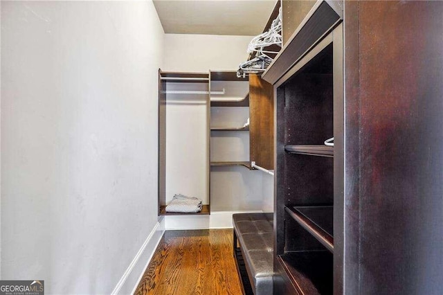 walk in closet with dark hardwood / wood-style flooring