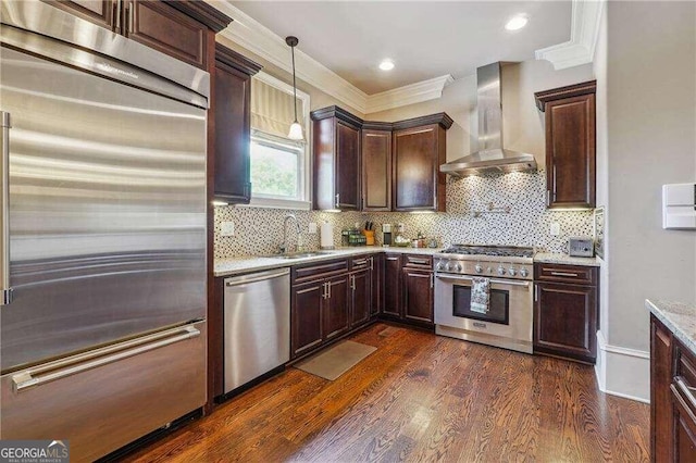 kitchen featuring hanging light fixtures, sink, wall chimney range hood, dark wood-type flooring, and high quality appliances