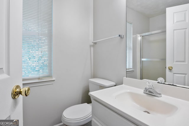 bathroom with a shower with door, vanity, a textured ceiling, and toilet