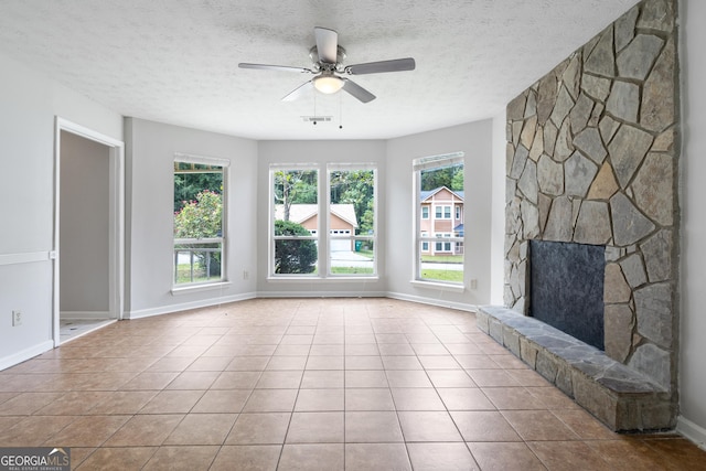 unfurnished living room featuring a textured ceiling, light tile patterned flooring, a fireplace, and a wealth of natural light