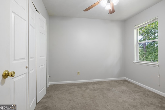 unfurnished bedroom featuring ceiling fan, a closet, and light carpet