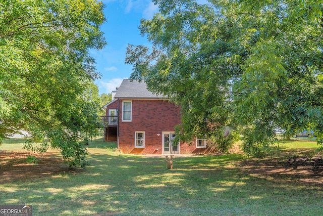 view of home's exterior featuring a yard, brick siding, and a deck