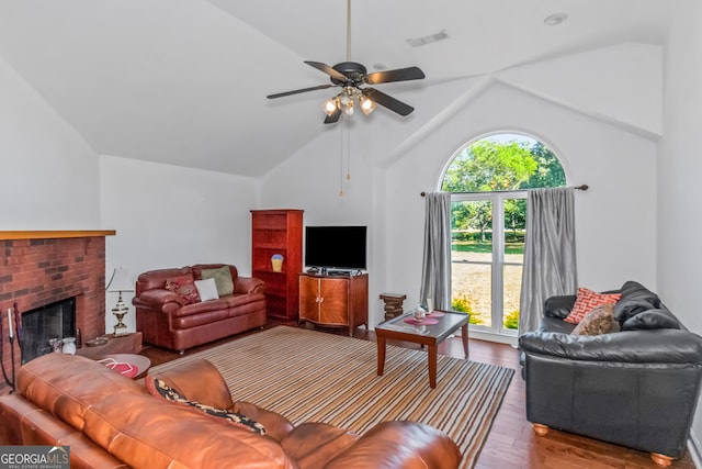 living room with lofted ceiling, hardwood / wood-style floors, ceiling fan, and a brick fireplace