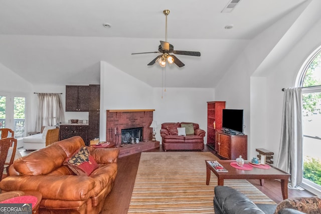 living area with lofted ceiling, a ceiling fan, and a brick fireplace