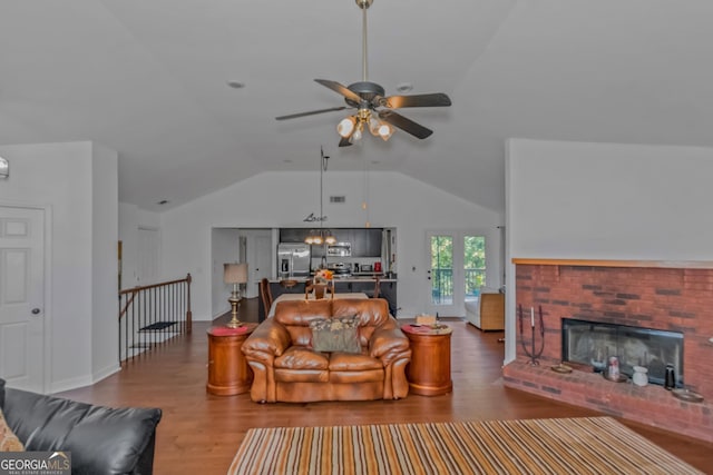 living room featuring ceiling fan with notable chandelier, lofted ceiling, a fireplace, and wood-type flooring