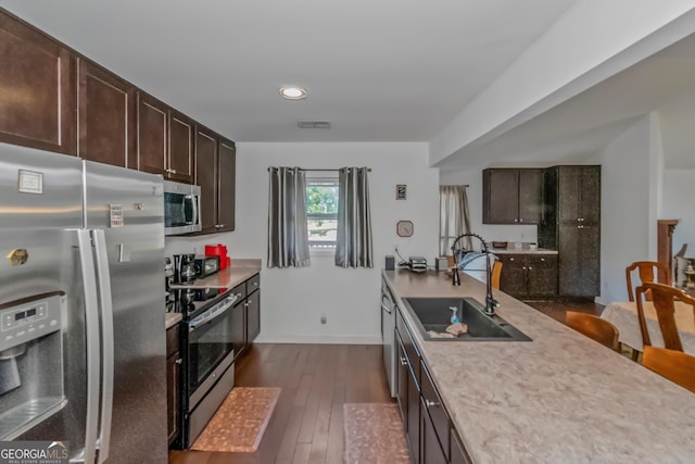 kitchen featuring dark wood-type flooring, stainless steel appliances, dark brown cabinets, and sink