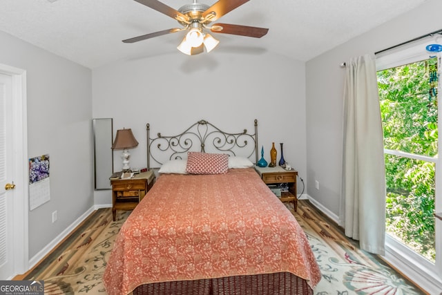 bedroom featuring wood finished floors, vaulted ceiling, baseboards, and a ceiling fan