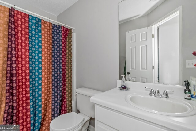 bathroom featuring toilet, a textured ceiling, and vanity