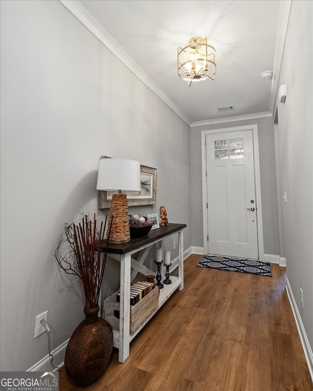 entryway with crown molding, wood-type flooring, and a chandelier