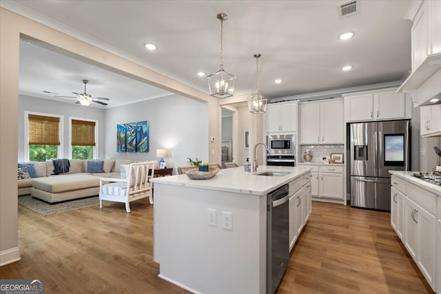 kitchen with appliances with stainless steel finishes, white cabinetry, sink, pendant lighting, and a kitchen island with sink