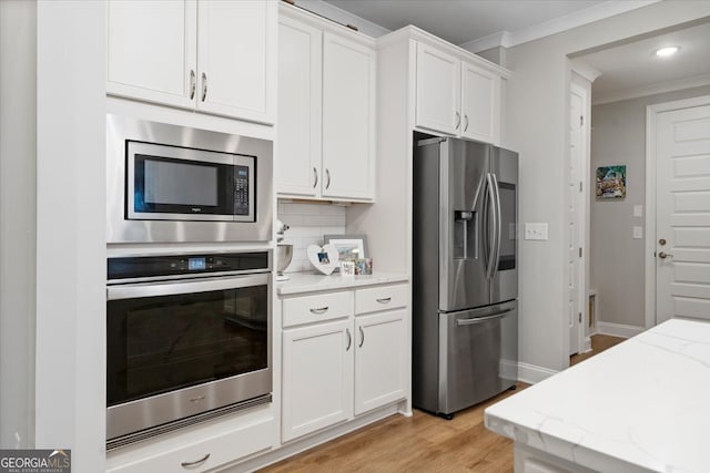 kitchen featuring stainless steel appliances, light stone counters, white cabinets, and light hardwood / wood-style floors