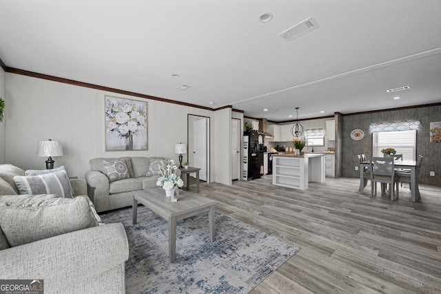 living room featuring crown molding and light hardwood / wood-style flooring