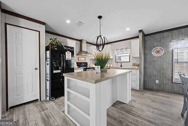 kitchen with black appliances, a wealth of natural light, wall chimney exhaust hood, and white cabinets