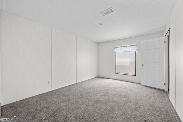 empty room featuring a textured ceiling and light colored carpet