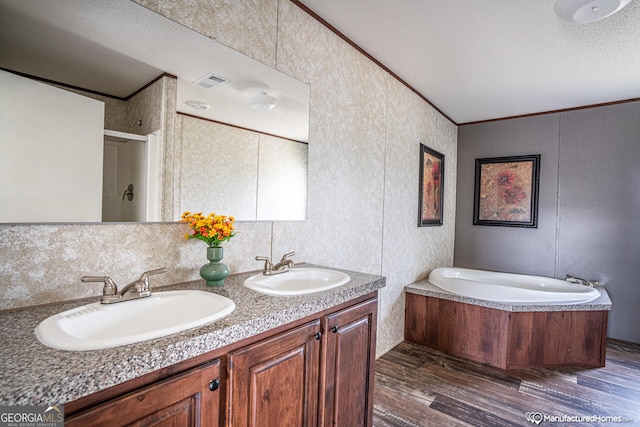 bathroom with a textured ceiling, hardwood / wood-style floors, shower with separate bathtub, vanity, and ornamental molding