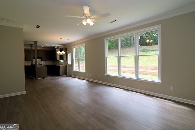 unfurnished living room with ceiling fan with notable chandelier, a wealth of natural light, dark hardwood / wood-style flooring, and crown molding