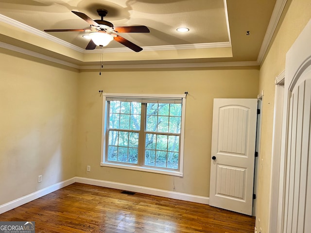 empty room featuring crown molding, a raised ceiling, hardwood / wood-style floors, and ceiling fan