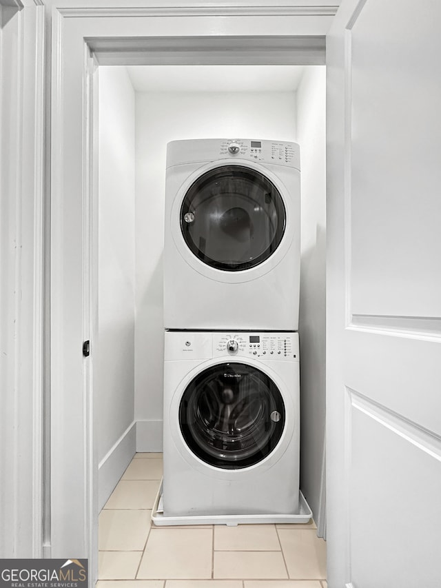 laundry room with light tile patterned flooring and stacked washing maching and dryer