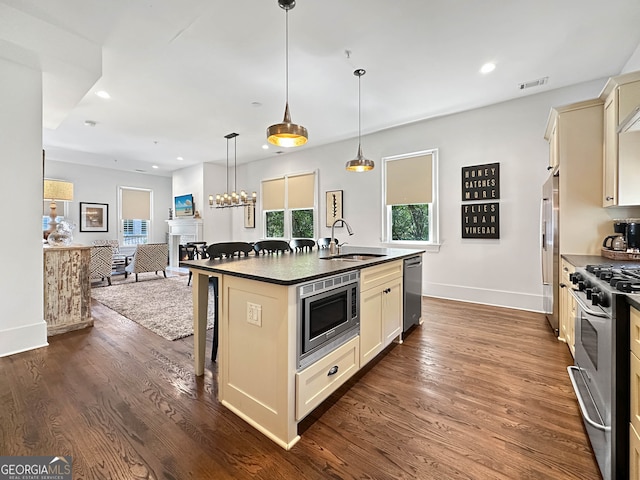 kitchen with a center island with sink, appliances with stainless steel finishes, dark wood-type flooring, a breakfast bar, and sink