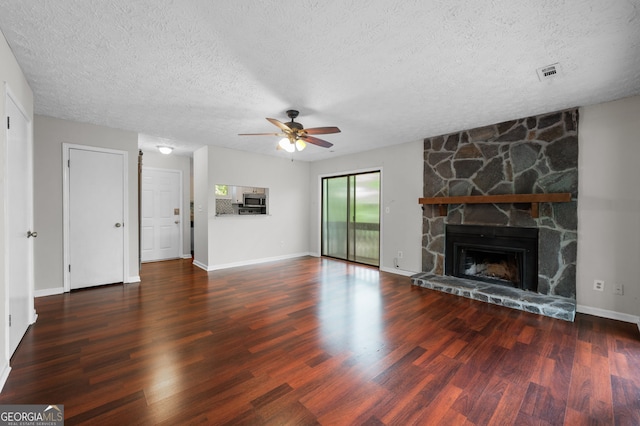 unfurnished living room featuring ceiling fan, dark hardwood / wood-style floors, and a stone fireplace