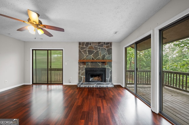 unfurnished living room featuring a textured ceiling, a stone fireplace, ceiling fan, and hardwood / wood-style flooring