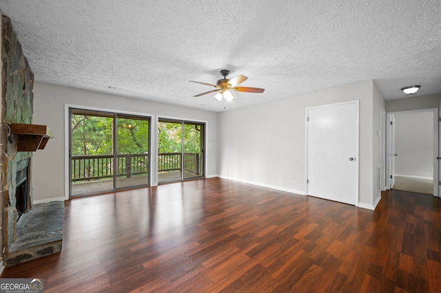 unfurnished living room featuring ceiling fan, a stone fireplace, a textured ceiling, and dark hardwood / wood-style floors