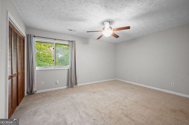 unfurnished bedroom with a closet, carpet, ceiling fan, and a textured ceiling