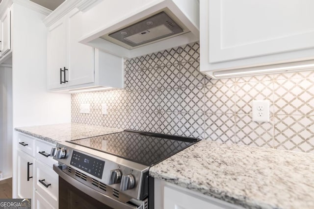 kitchen with premium range hood, white cabinetry, stainless steel electric range, light stone countertops, and decorative backsplash